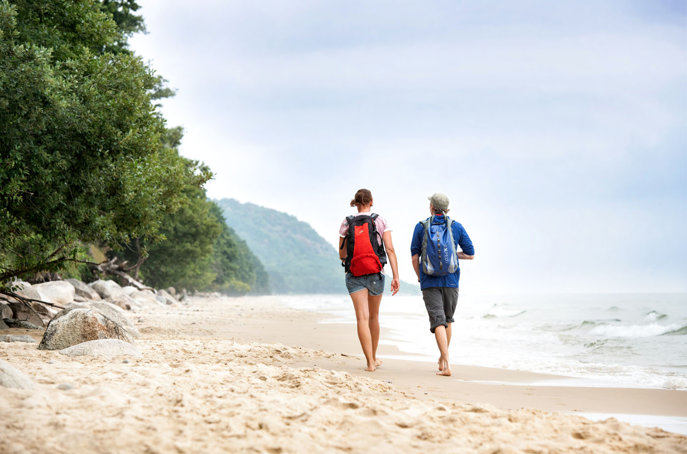 Man and woman walking a long a beach in the summer