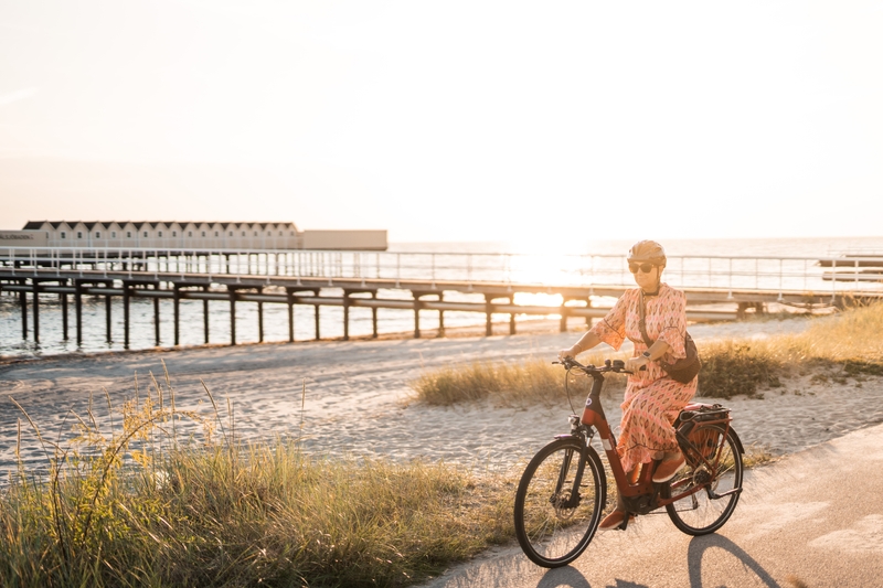 Woman biking along the a beachwalk during the summer