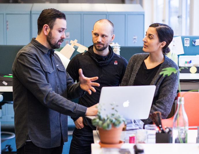 Three collegues discussin something on a laptop screen