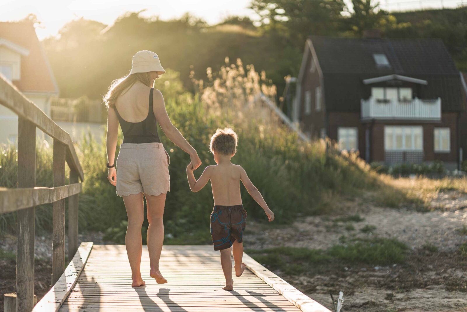 Woman and child walking hand in hand by the beach