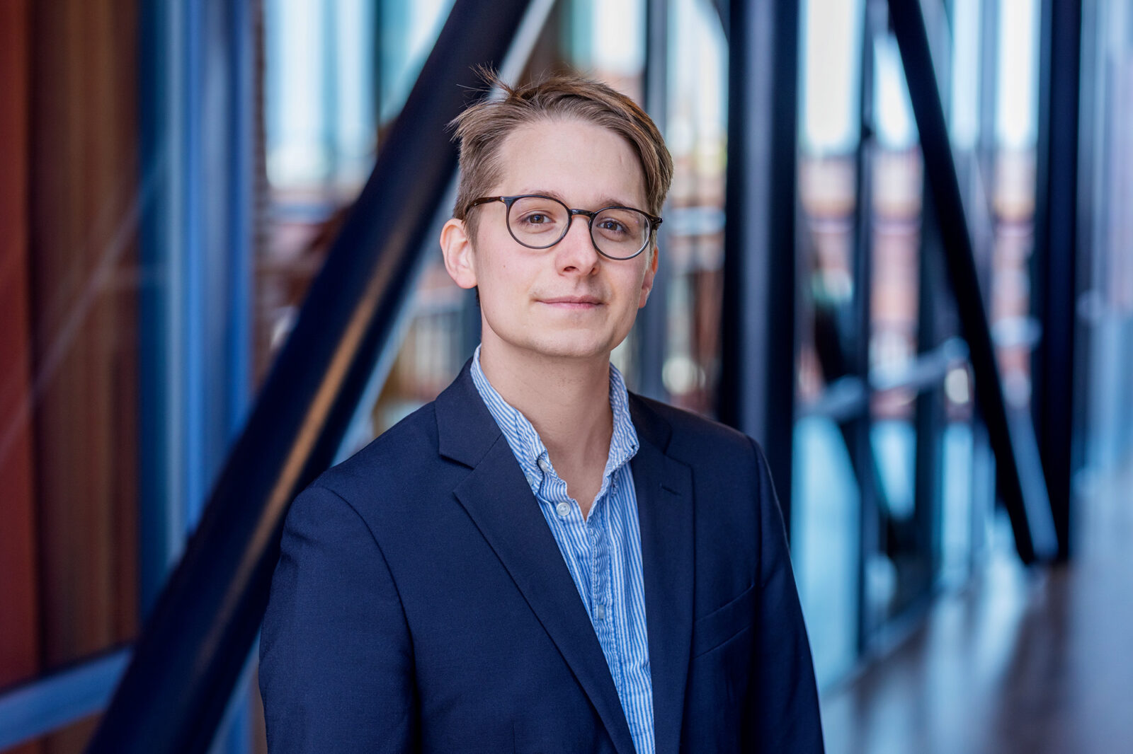 A portrait photo of a man. He is wearing a blue shirt and a blazer jacket.